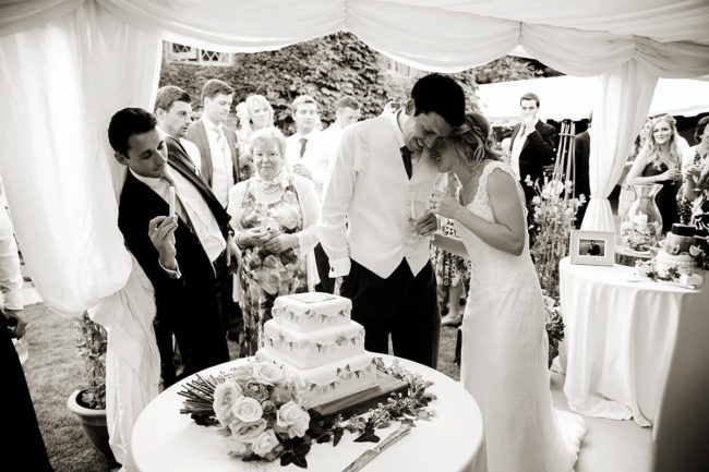 Sussex Marquee Wedding – 1 a bride & groom cutting their wedding cake in a marquee