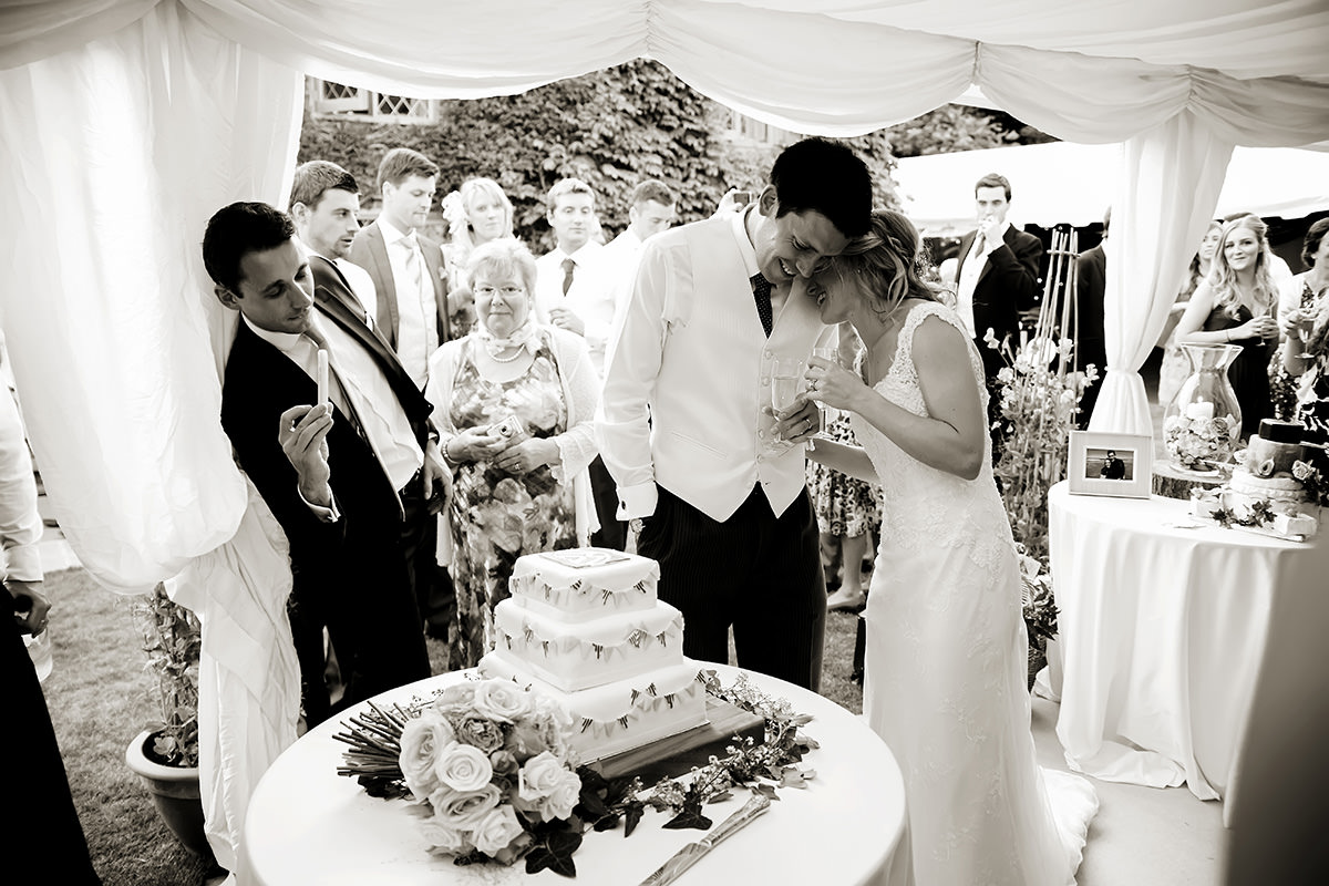 a bride & groom cutting their wedding cake in a marquee