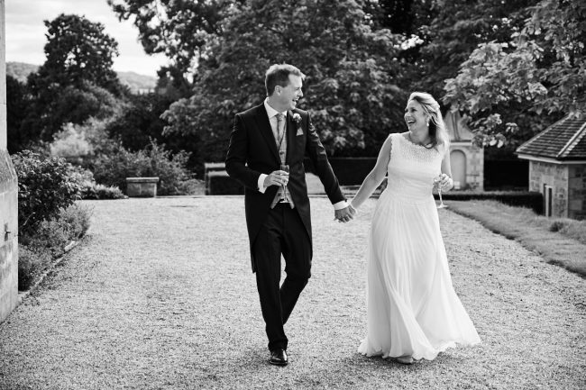 Cowdray House wedding photographer – 200 a bride and groom walk and laugh together during their wedding at Cowdray House in West Sussex