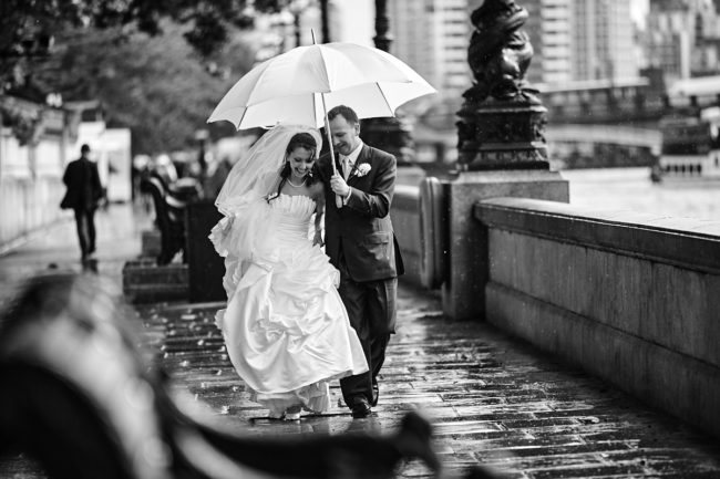 Umbrella – 1 a bride and groom laughing in the rain under an umbrella