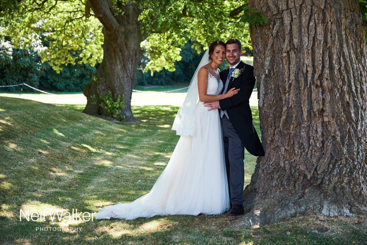 the bride and groom leaning against a tree