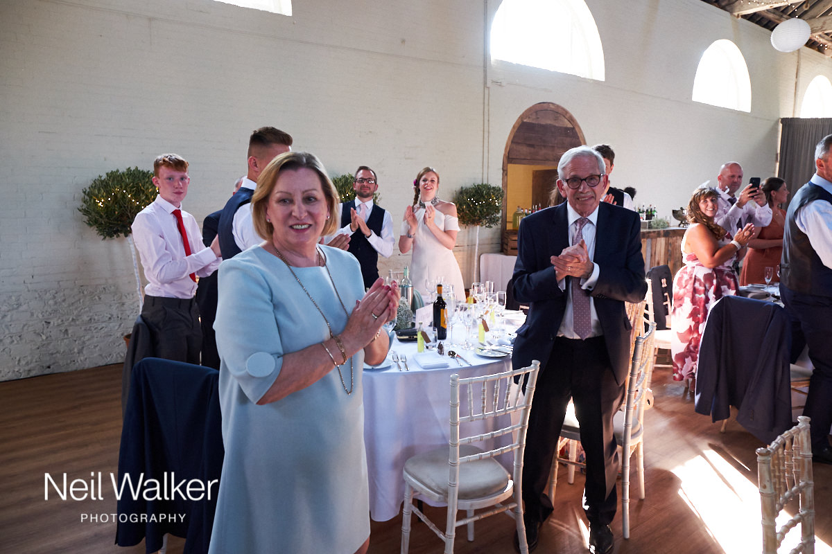 guests laughing as they clap the bride and groom into the wedding breakfast