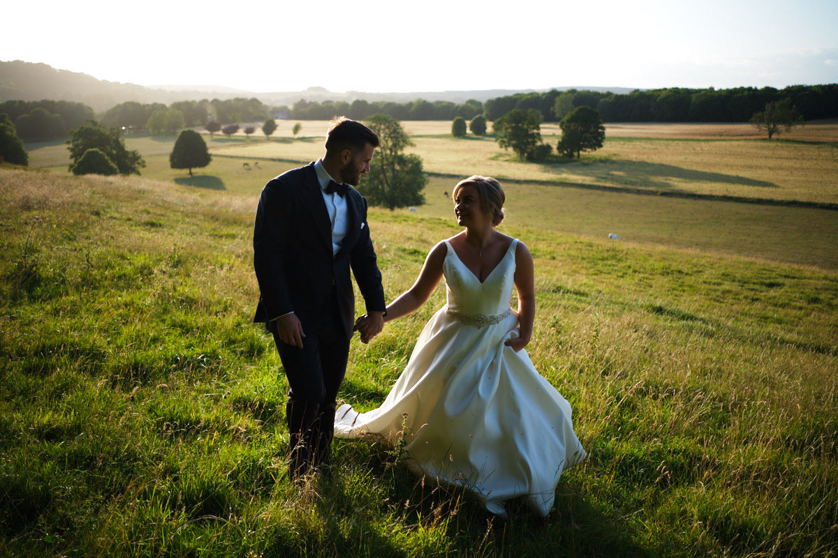 Cissbury-Barns-Wedding-Photographer-0127 A bride and groom walking across the South Downs, photographed by Cissbury Barns wedding photographer Neil Walker.