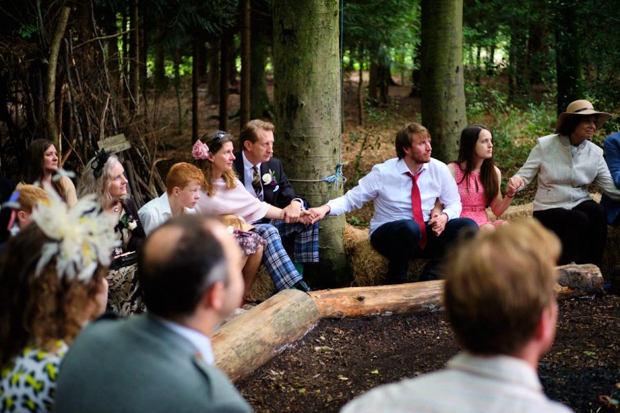 Guests holding hands during a wedding ceremony at Wilderness Wood.