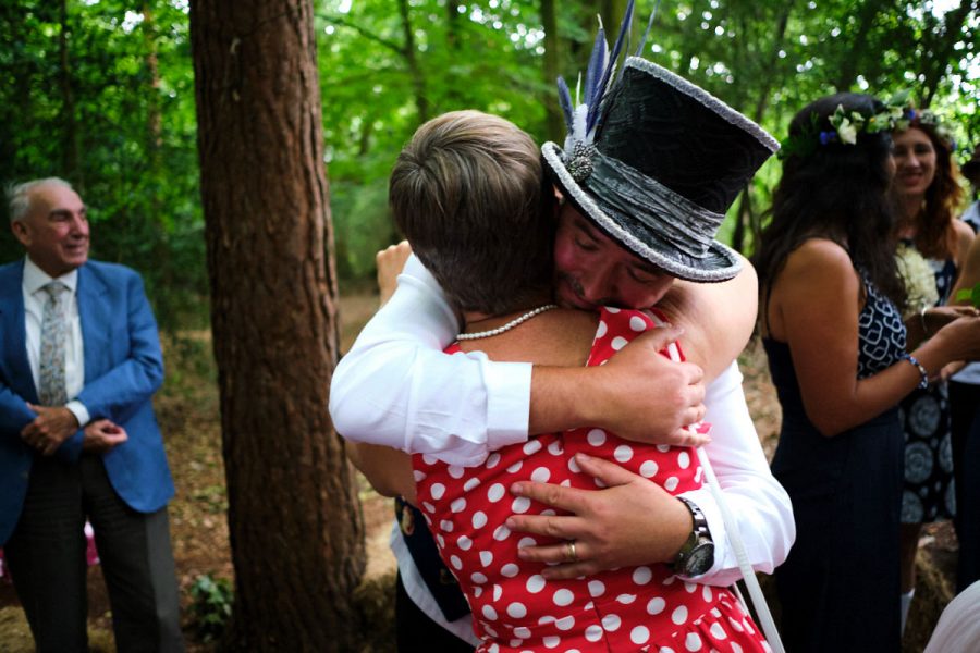 The groom hugs the bride's mother at a wedding at Wilderness Wood in East Sussex.