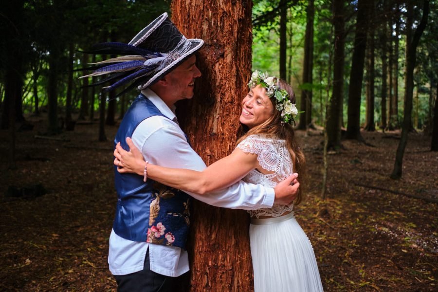 The bride and groom at their wedding at Wilderness Wood hugging a tree.